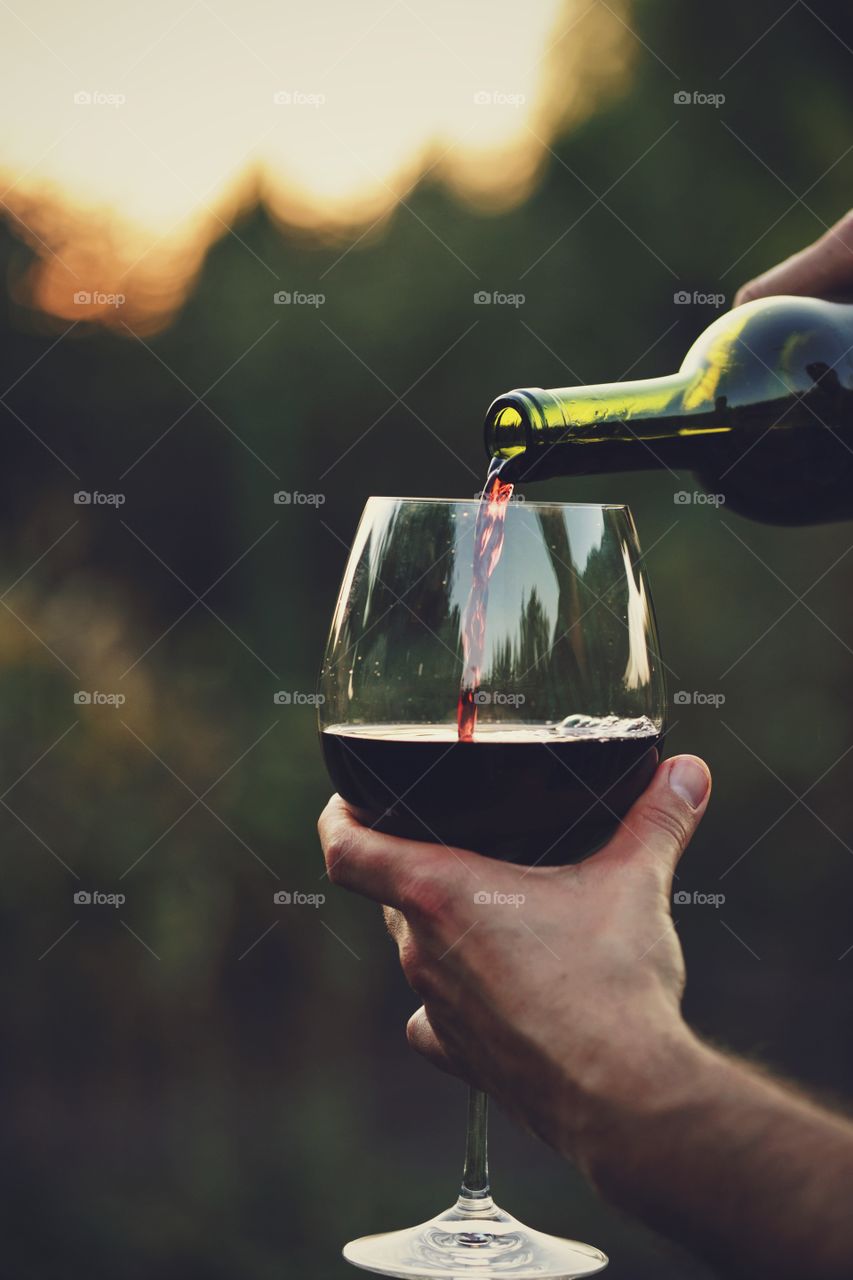 Close-up of hand pouring wine in wine glass