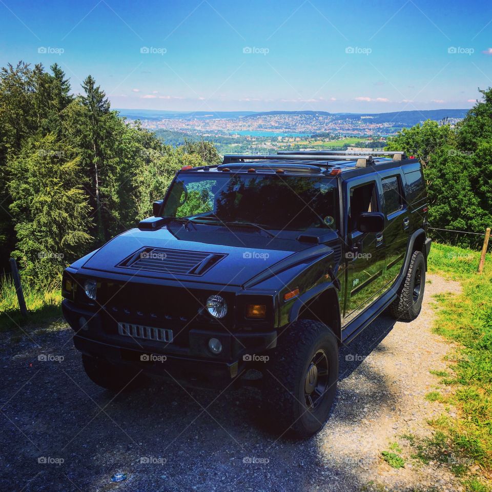 Hummer H2 in nature with city in background during summer