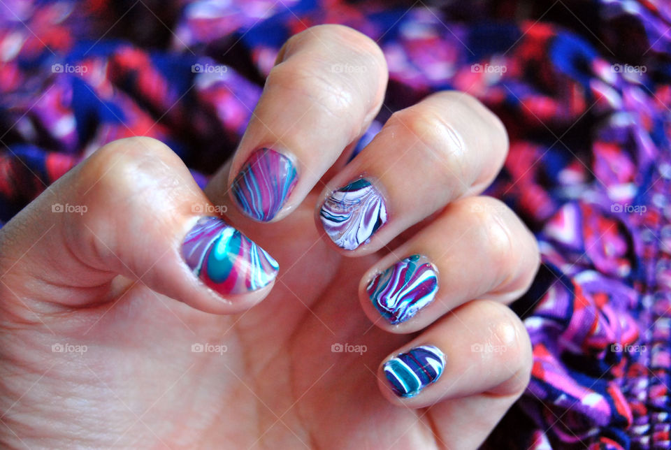water marble nail art in purple, magenta, bluegreen and white. close-up