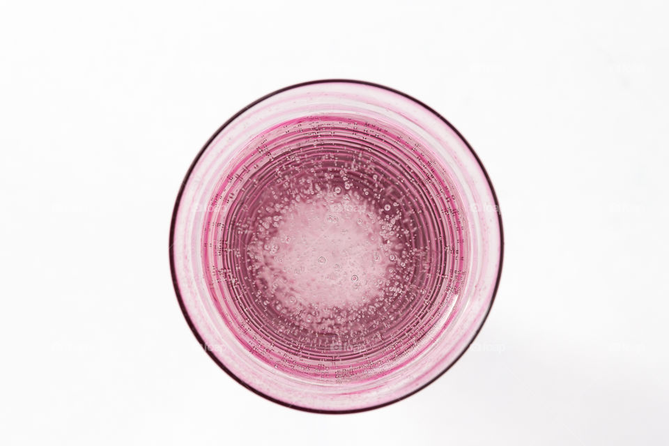 Round, pink striped glass filled with sparkling water 