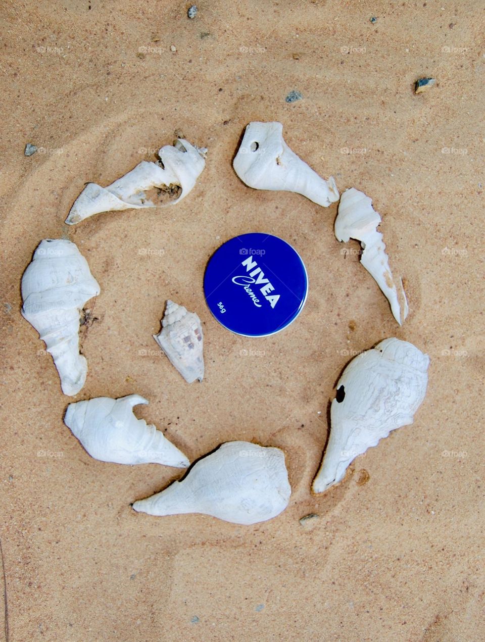 Nivea cream in sand inside shells circle 