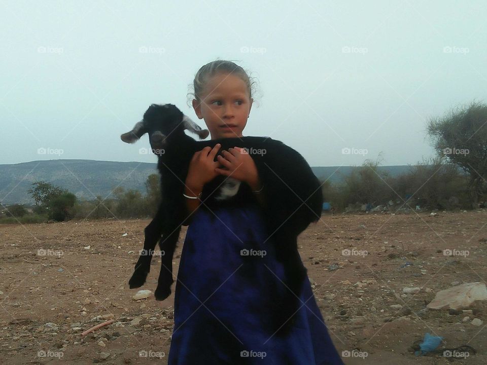 Beautiful girl holding a baby goat.