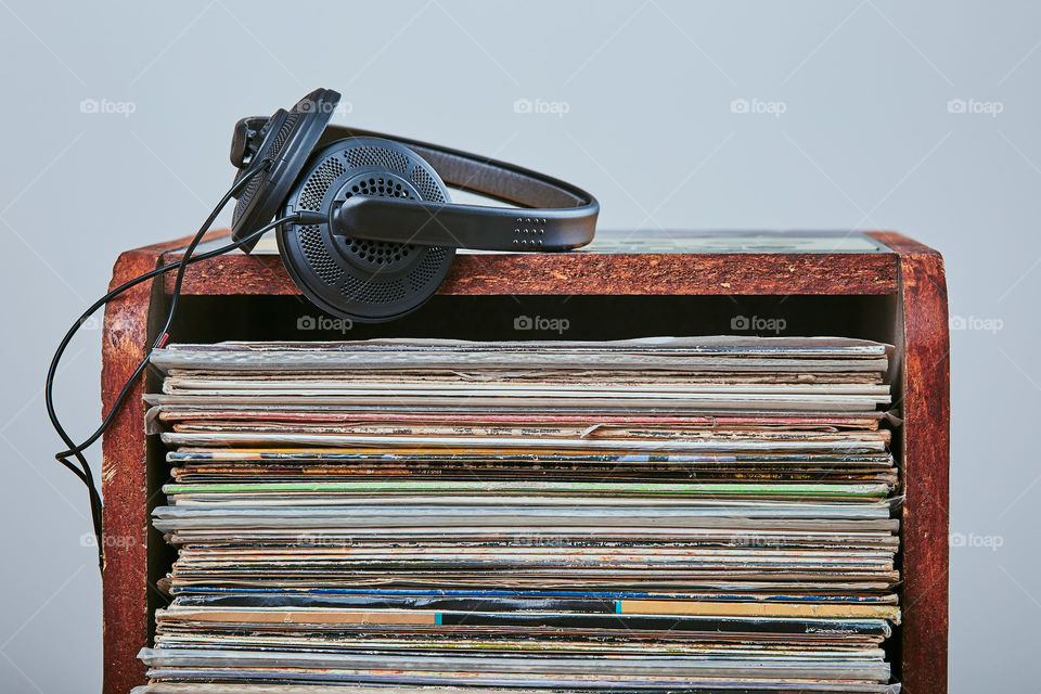 Stack of many black vinyl records and headphones put on the top of stack. Candid people, real moments, authentic situations