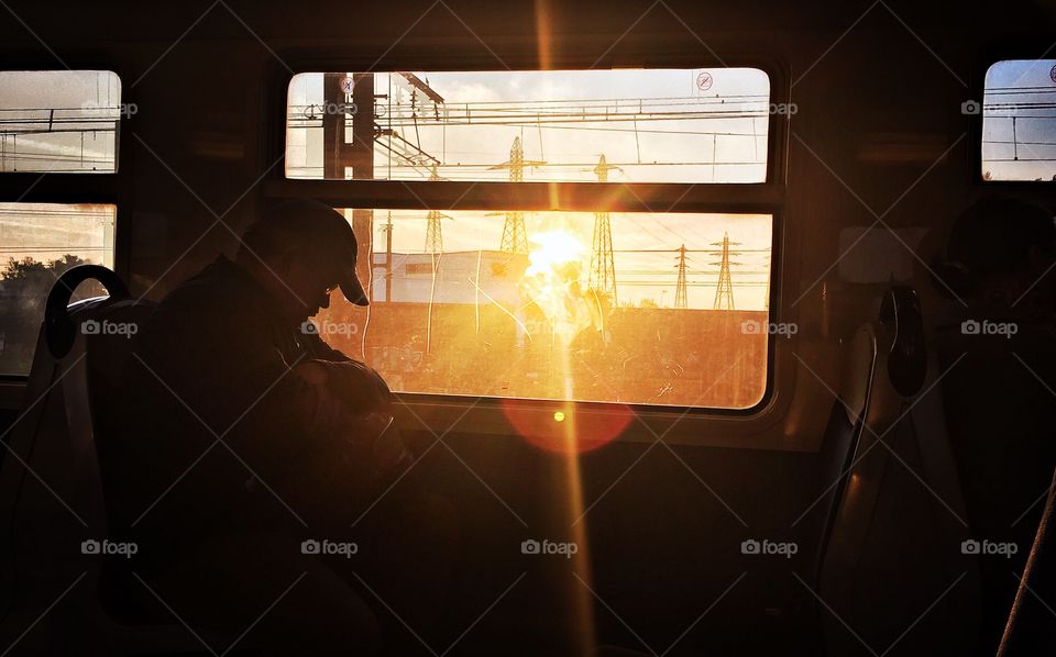 Tired man sleeps on train at sunset 