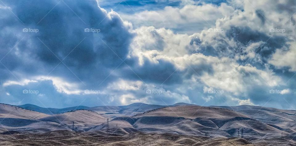 Rolling hills along highway 5 southbound in California with orchards and stunning cloud formations on a beautiful afternoon 