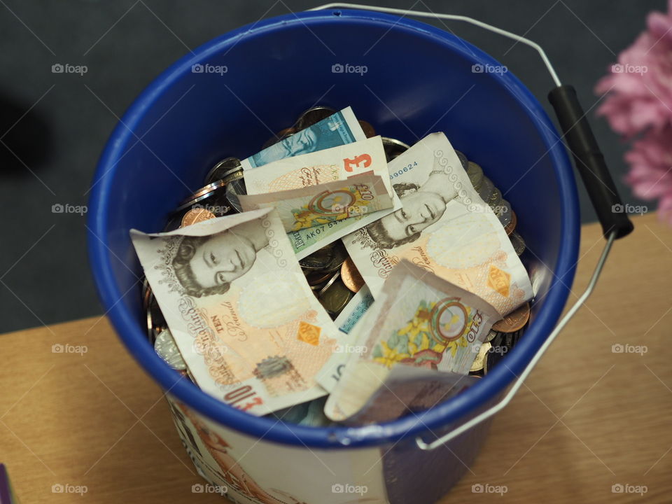 Fundraising bucket full of British money