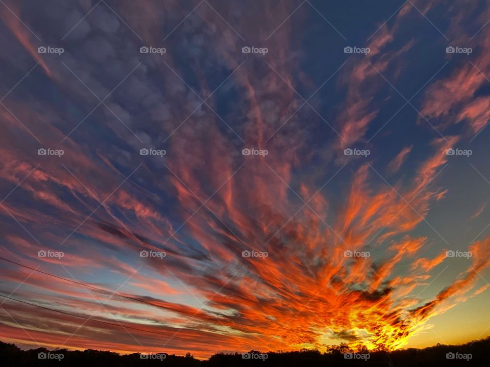 A stunning mid west Prairie sunset in the country, filled with flame-like cloud shapes with amazing vivid colors to match. Beautiful cloudscape patterns with majestic color scheme to match.