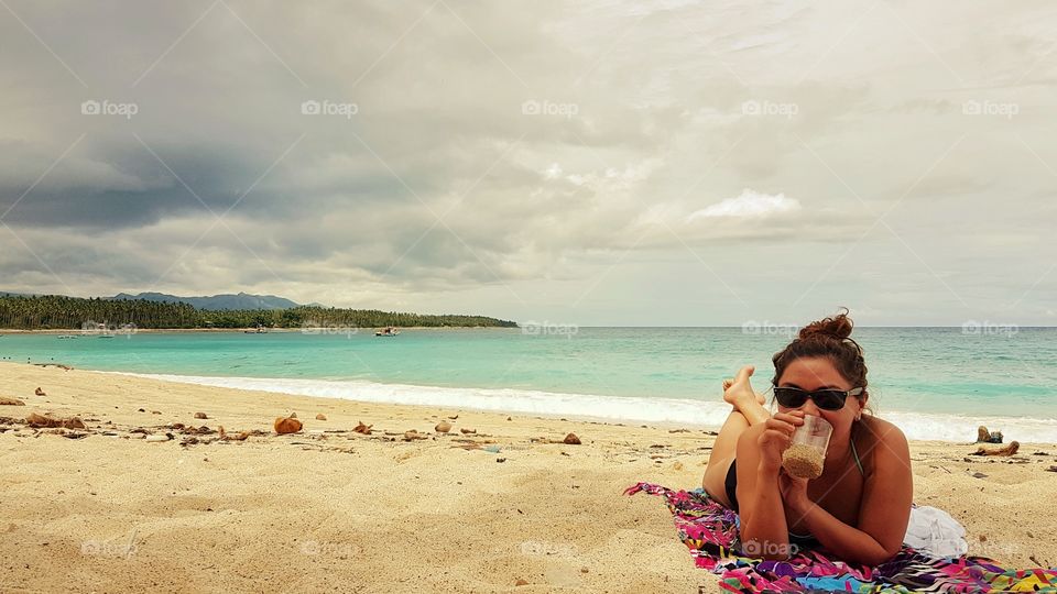 girl sunbathing and drinking beer by the beach