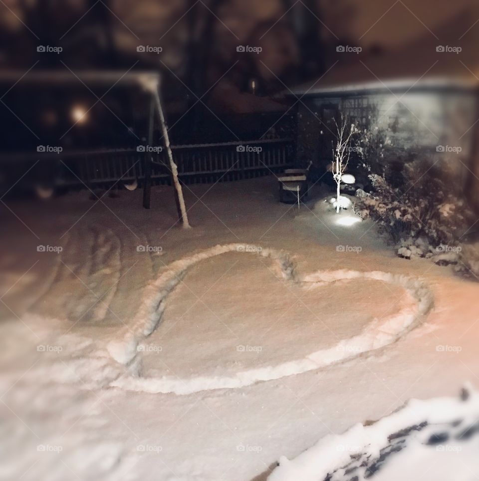 Points of light shine on soft snow where a lovely heart is traced. 