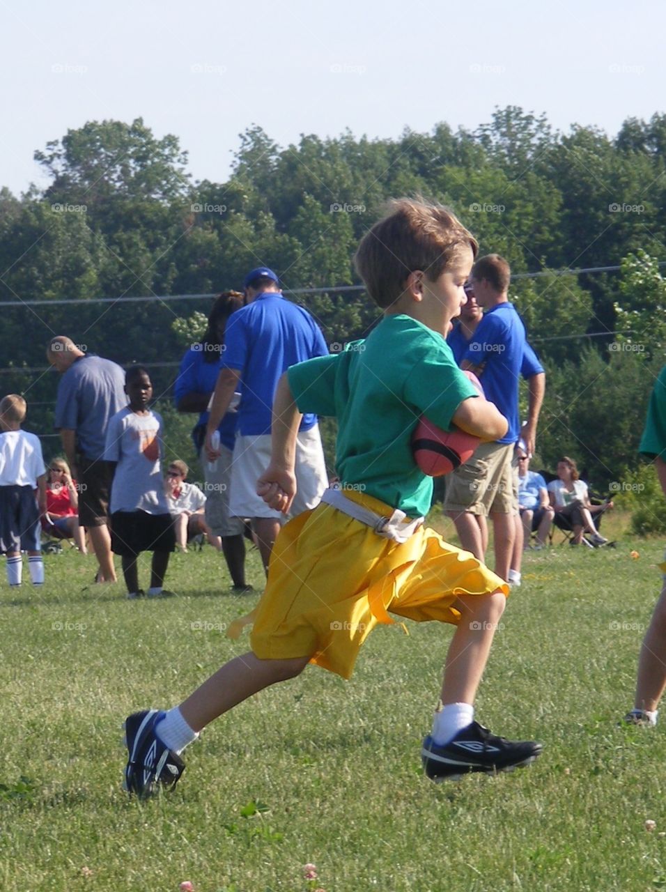 Little boy running with football, flag football