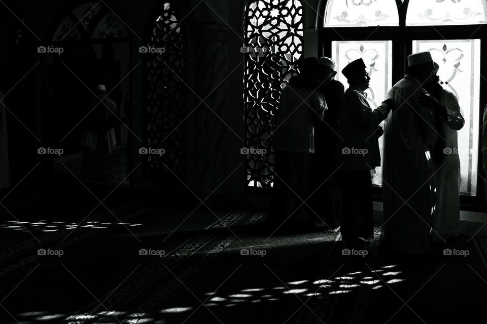 Black and white portrait of Eid al-Fitr prayer congregation shaking hands and saying sorry.