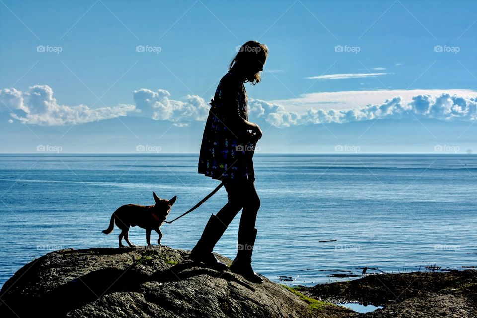 Girl walking her dog on rocky hill against magical backdrop 