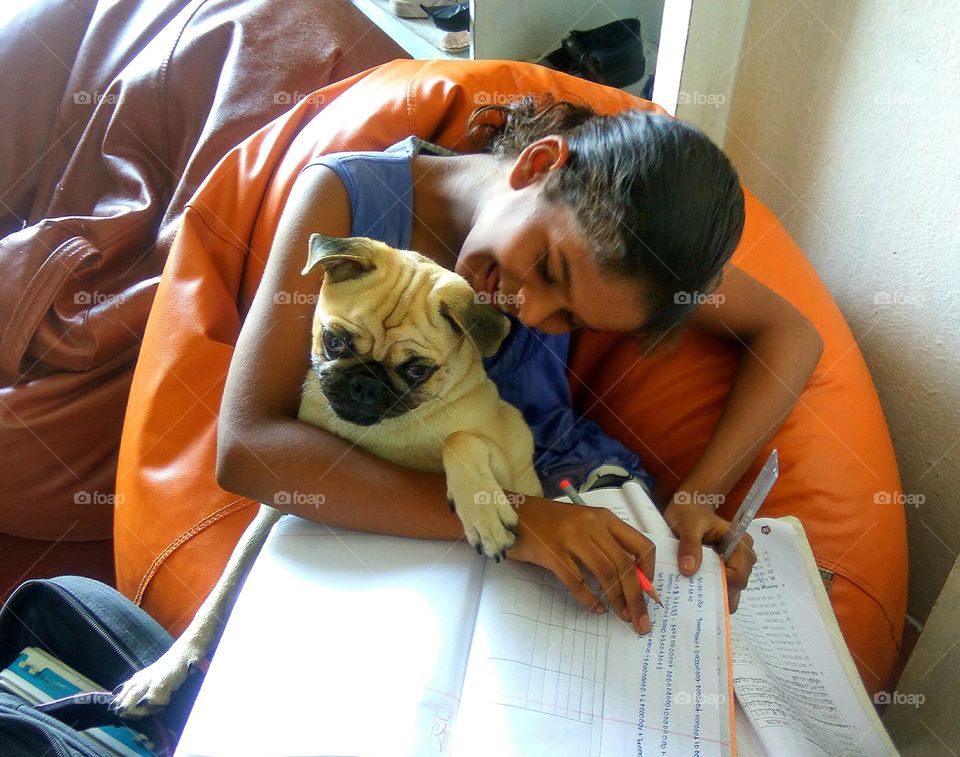 Girl holding dog while studying