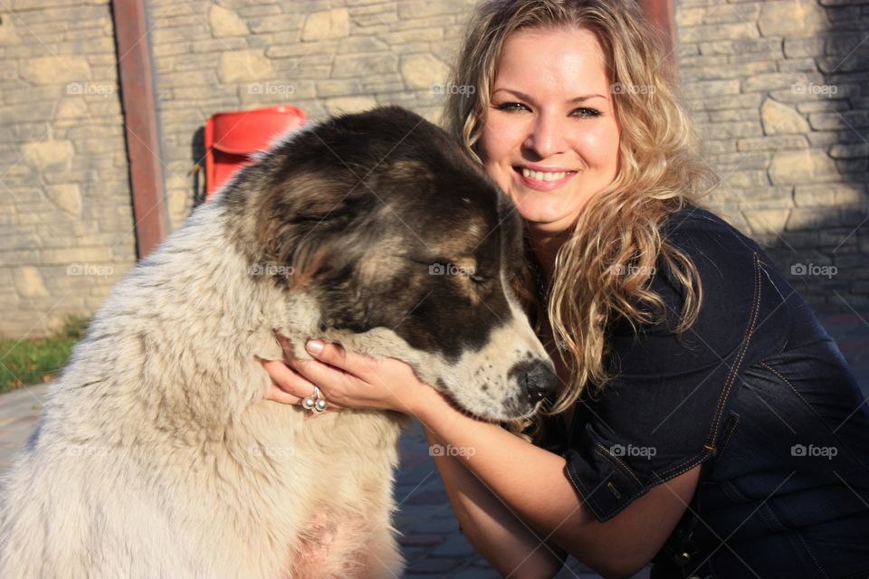 Pretty long curly hair blonde girl hugging big dog 
