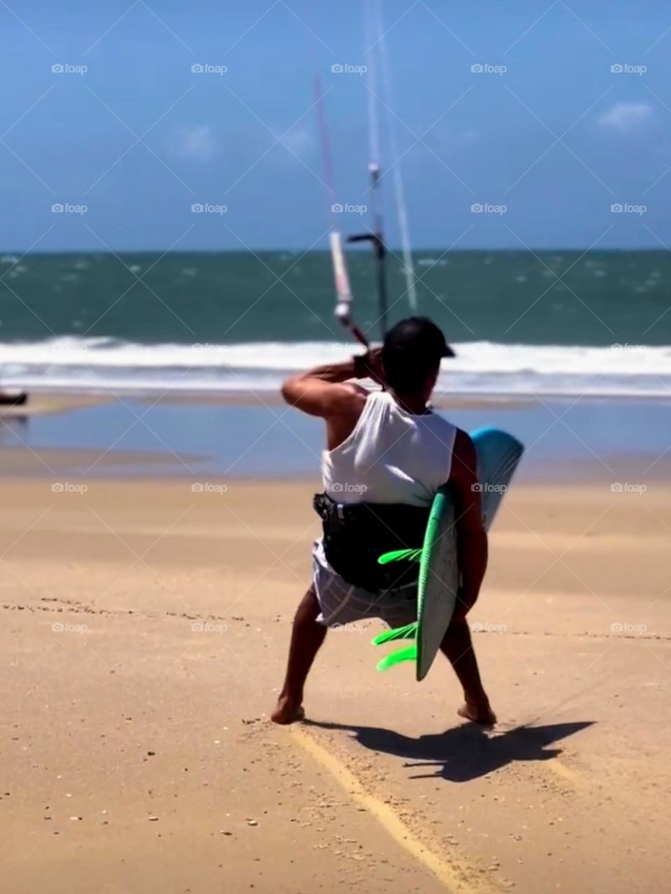 Man preparing to enter the sea with a kitesurfing board