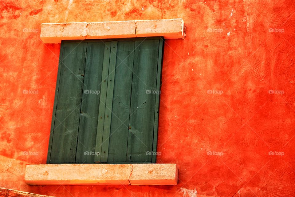 Wooden window closed on the orange wall.