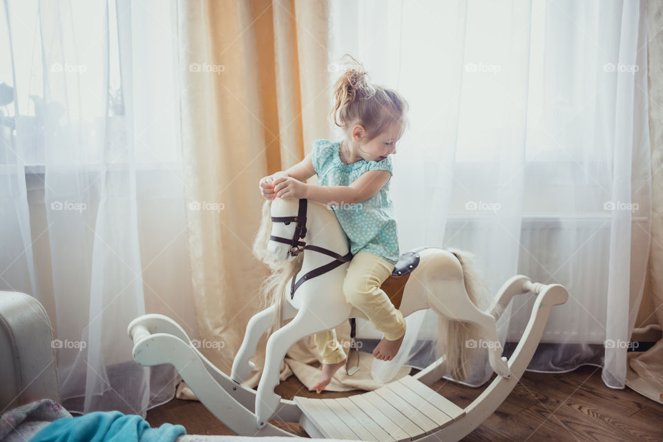 Little girl on rocking horse at daylight 