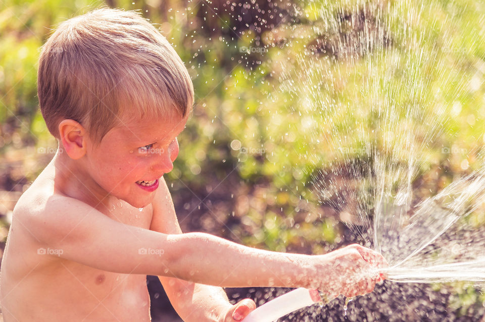 Boy is playing with water in the garden