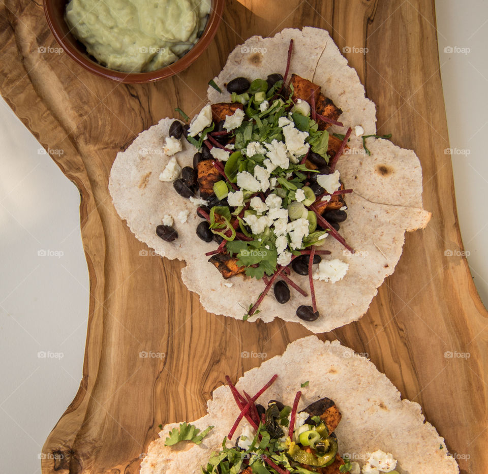 Black bean and roasted sweet potato tacos with feta and avocado cream