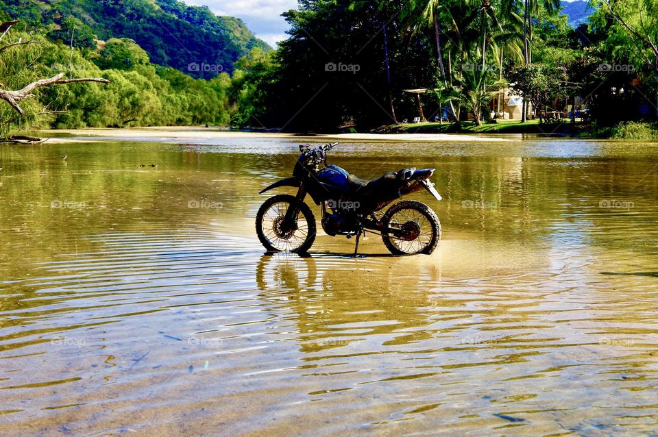 A dirt bike in the middle of the river.