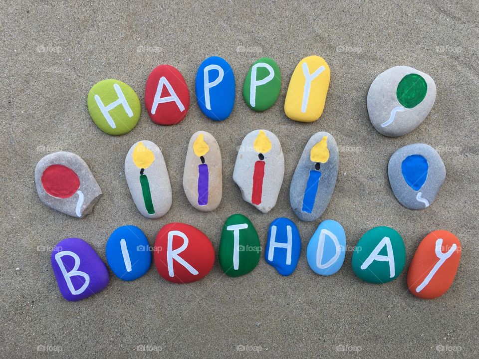 Happy Birthday composition . Colored stones composition with candles and balloons on stones