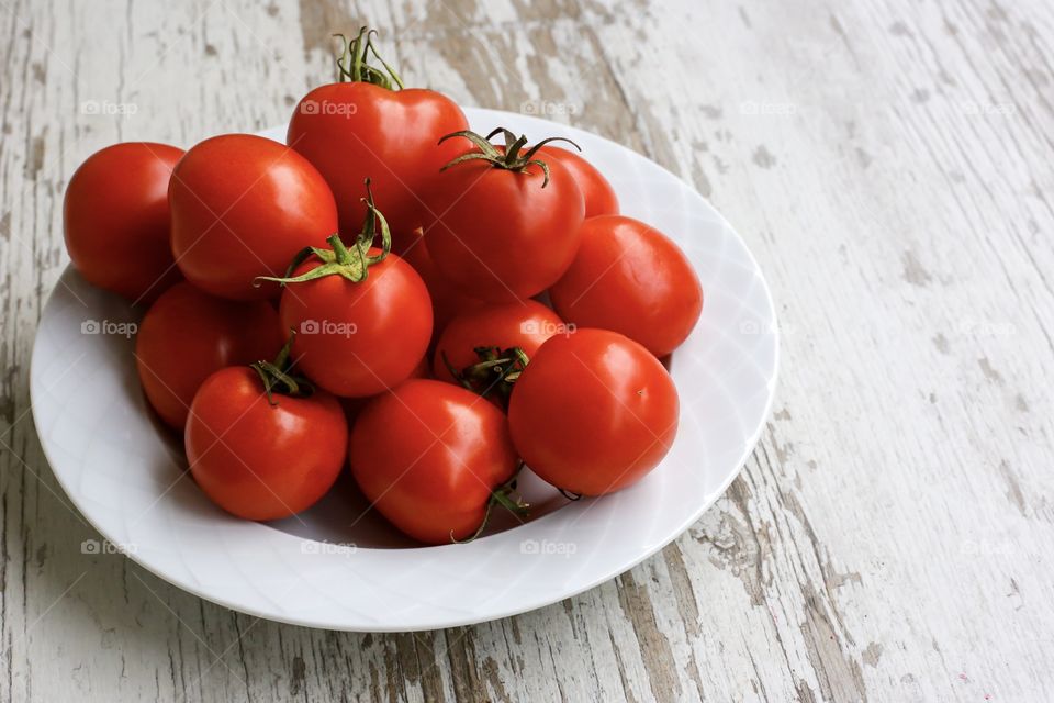 Bright tomatoes on the white plate 