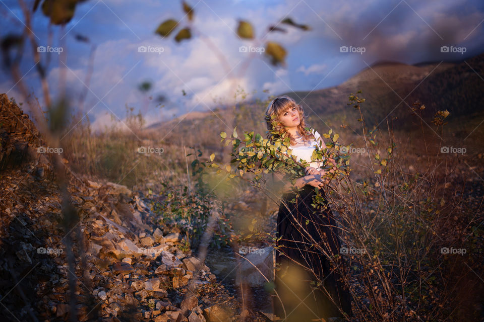 Pretty woman holding branch of plant in hand