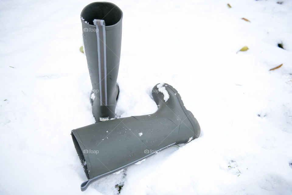 Pair of tall green rainboots in the snow outdoors