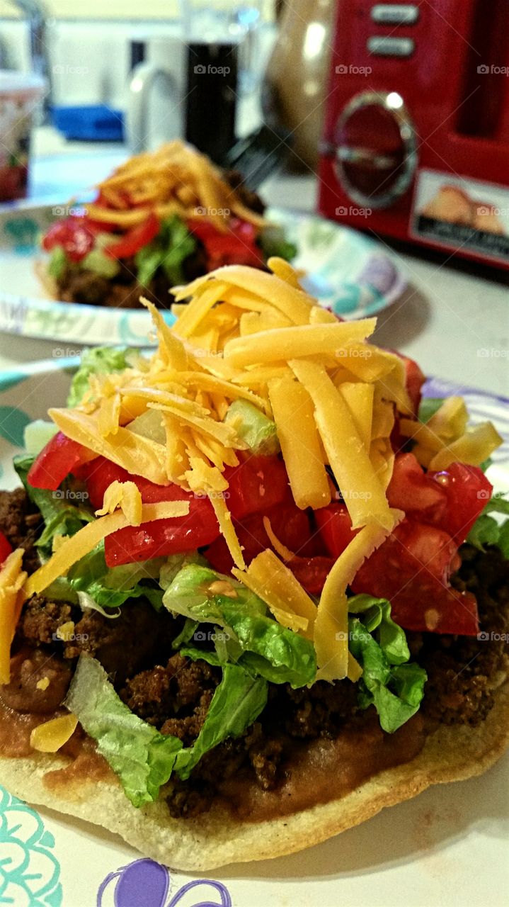 Tostadas made with ground beef, fresh lettuce and tomatoes and topped with grated cheddar.