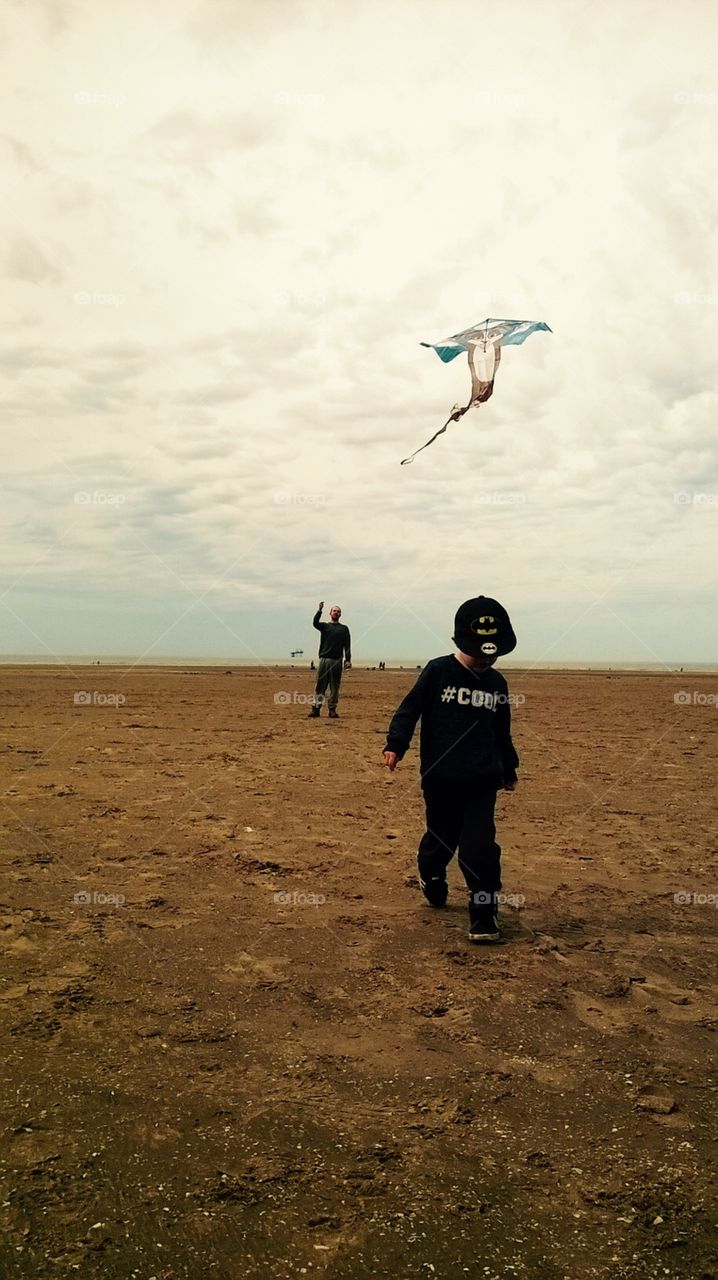 This is my son, Austin and his dad in the background. The photo was taken on a very windy day at a beach in Southport, UK. We decided it was perfect for flying this cute kite we had got prior and I captured this snap as Austin was walking towards me.