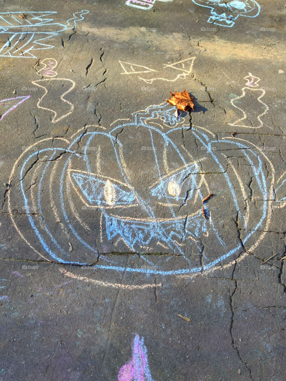 halloween.  Children's drawing on the asphalt with multi-colored chalk.  Scary pumpkin