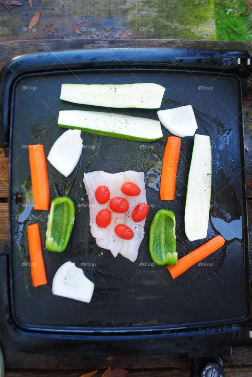 Cooking fish with vegetables at the grill outside