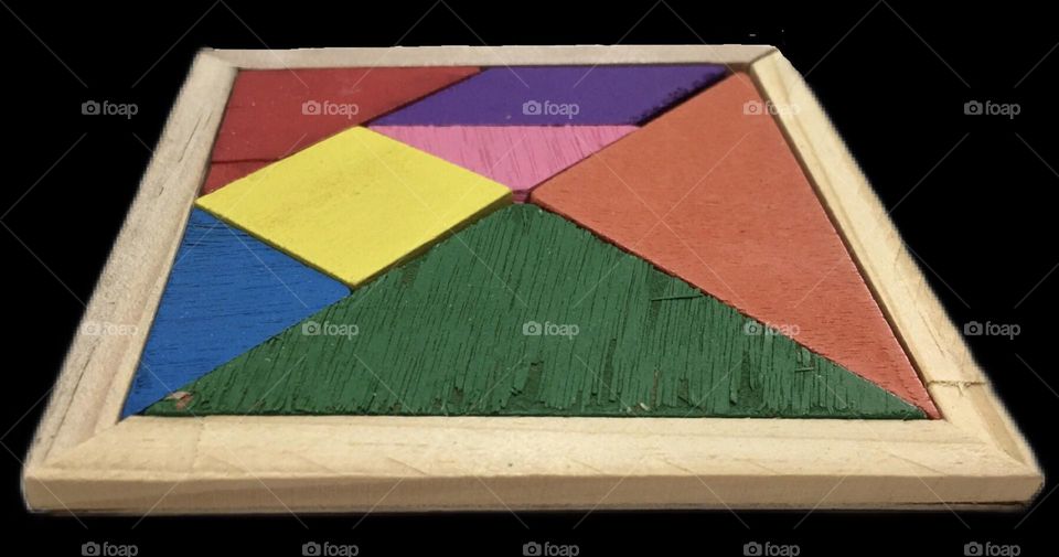 A board of wooden colored tangram puzzle pieces surrounded by a neutral color frame