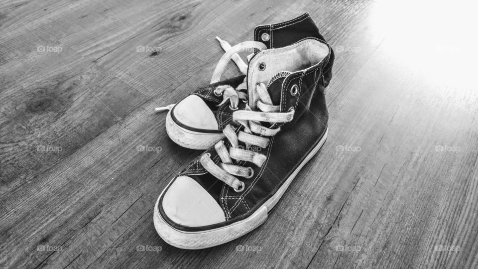 black and white worn canvas sneakers on a wooden empty copy space background