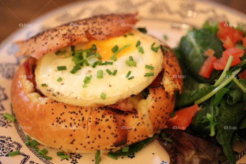 Egg baked inside a bread bun for breakfast on a chintzy plate. 