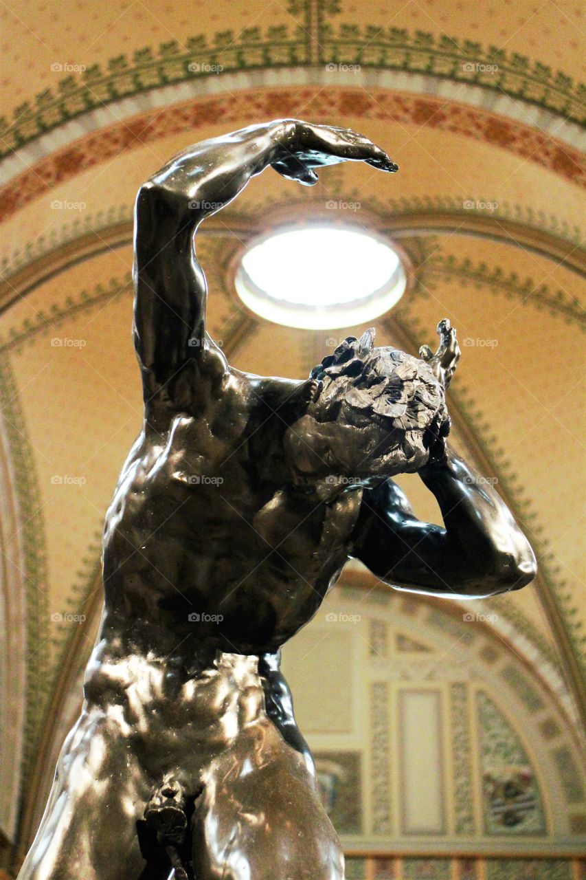 It looks like the statue carries something over the shoulders but it is actually the roof of the dome from Rijksmuseum, Amsterdam