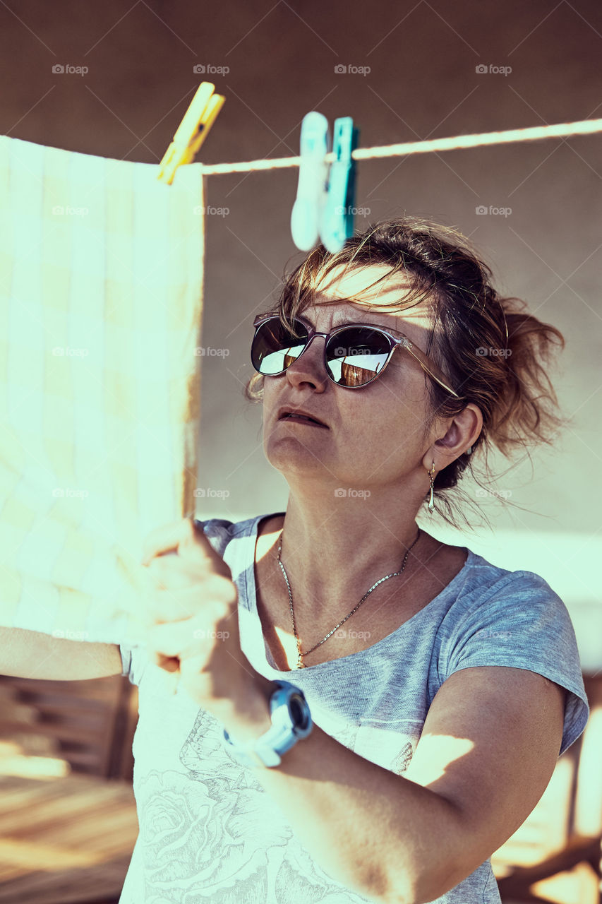 Adult woman hanging a laundered cloth on clothesline. Real upeople, real, authentic situations