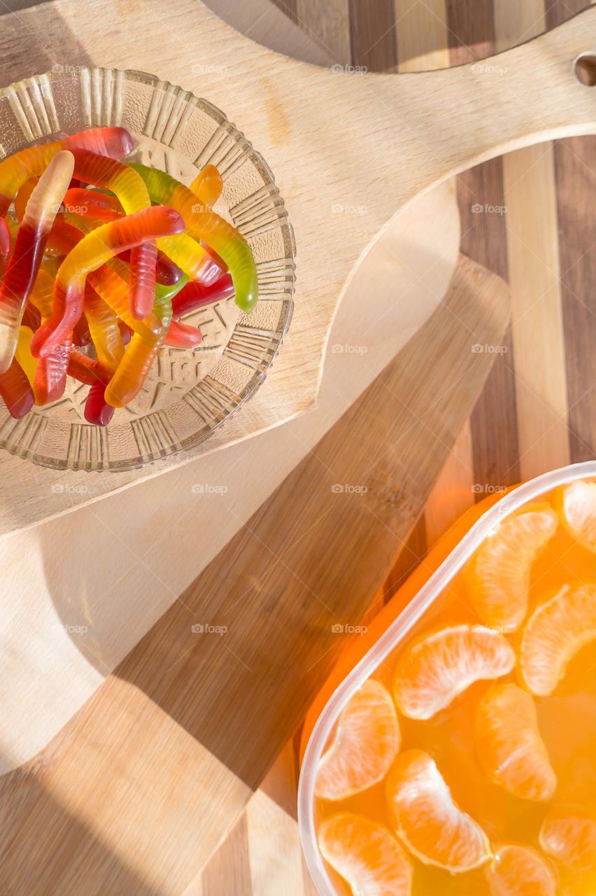 Delicious orange jelly with tangerine slices in a container and jelly worms.