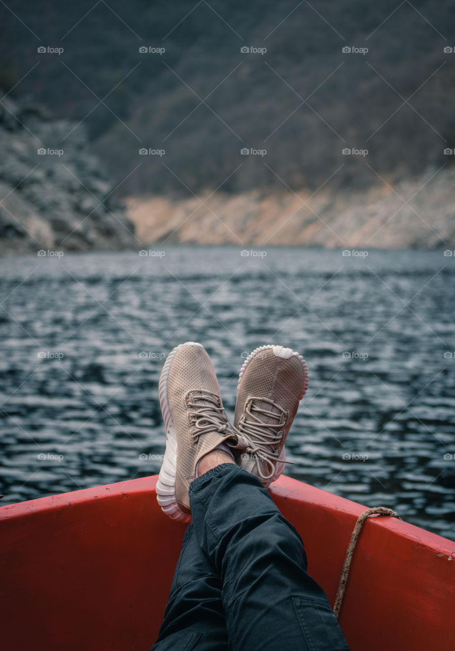 Man holding feet up in a boat in the middle of the lake.