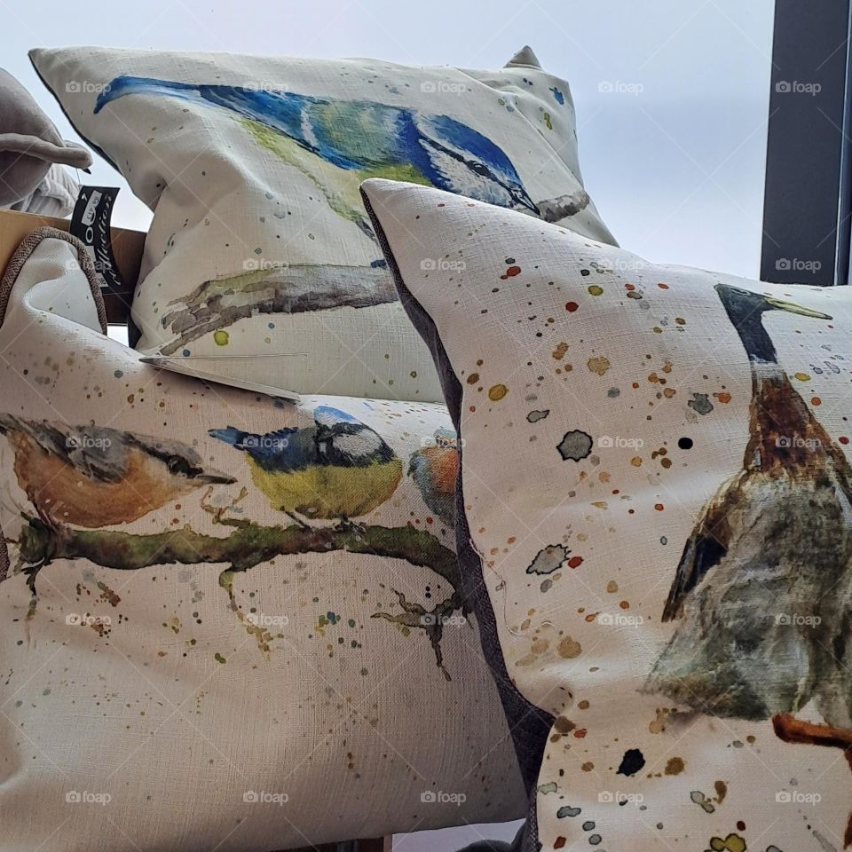 3 plump cushions with different designs on a shelf to sell