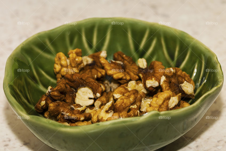 A beautiful textured green bowl full of delicious pecan nuts