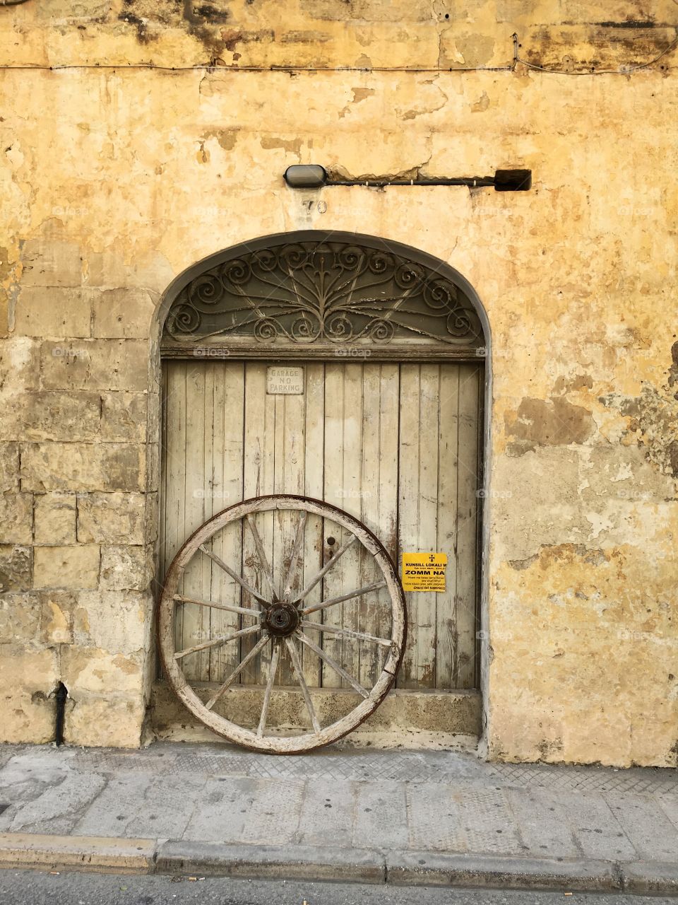 Old wooden wheel beside garage