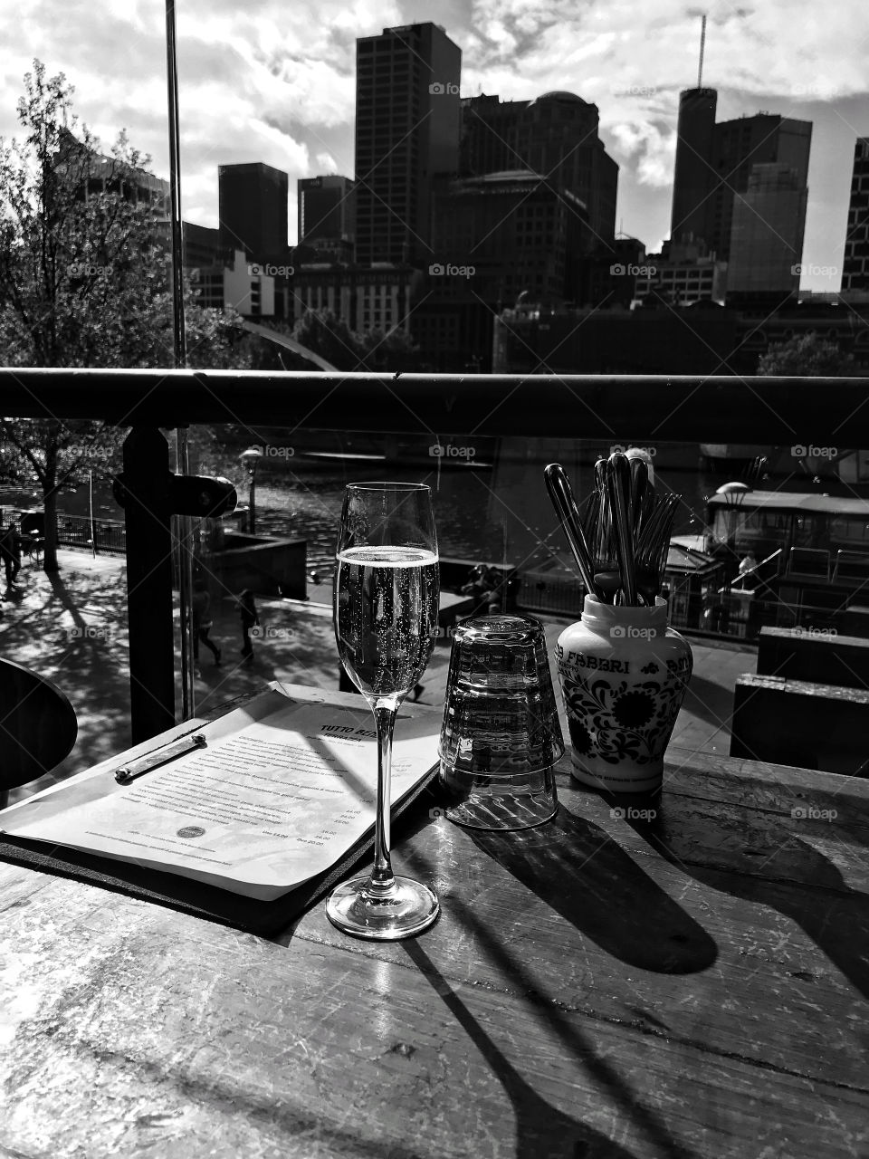 Glass of champagne with Melbourne in background in black and white 