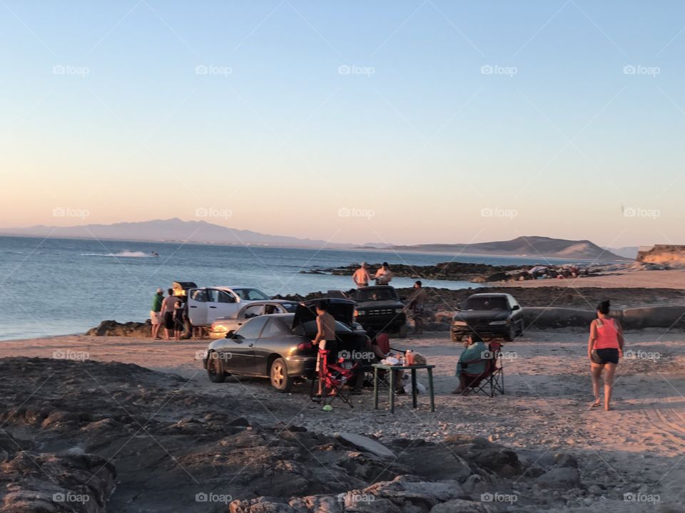 A family preparing a barbecue at a rocky beach in Mexico