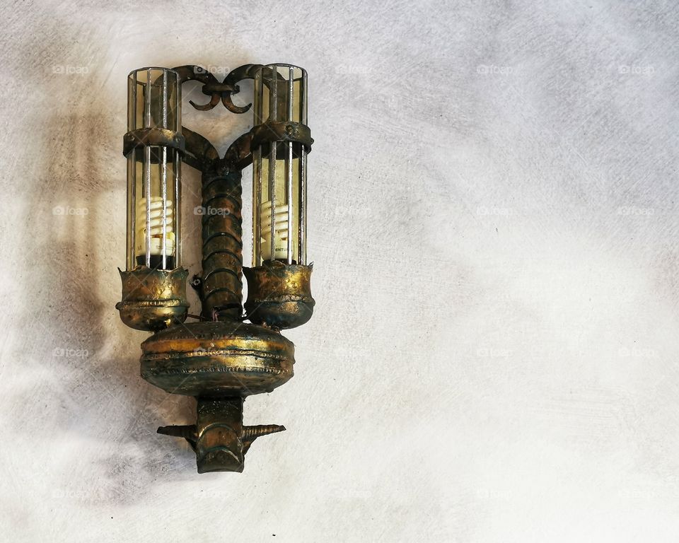 Old decorative ancient vintage brass lamp on the concrete wall with copy space.
