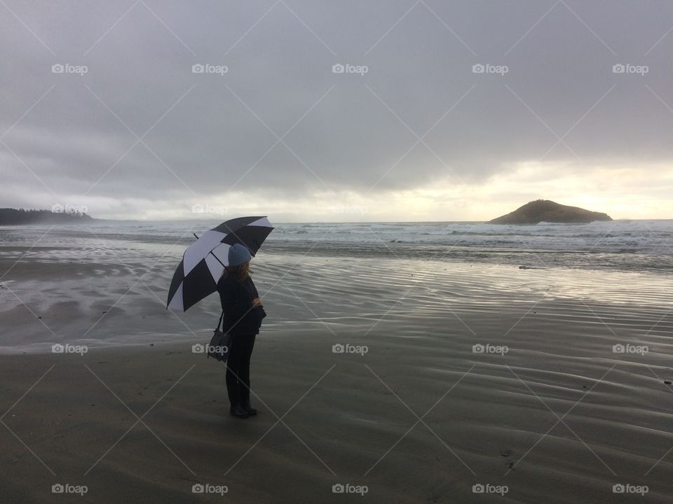 Girl on the beach with umbrella on a stormy day. 