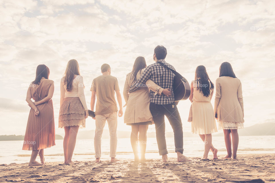 Rear view of friends standing at beach