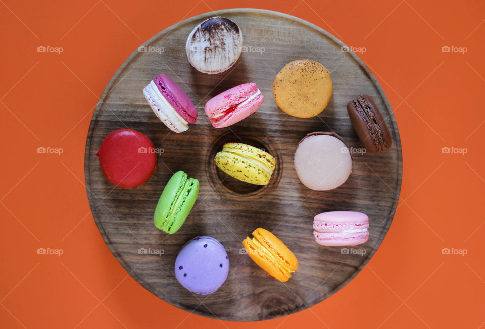 Macaroons desserts on the round wooden plate, view from above, flat lay food
