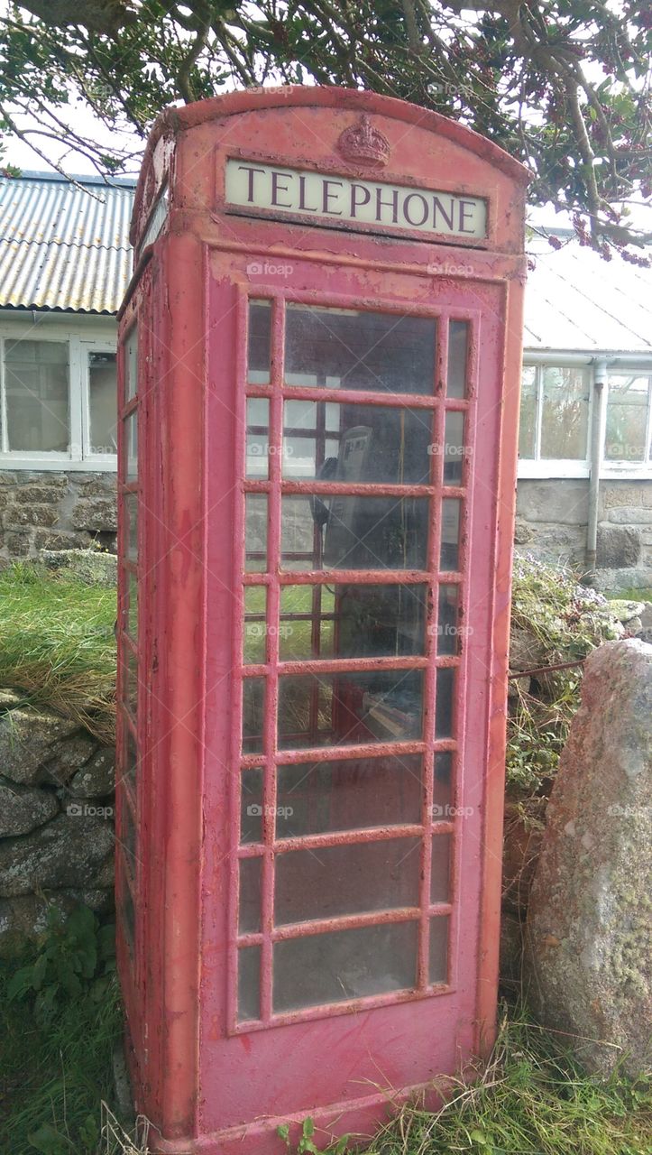 rusty red English phonebox in village