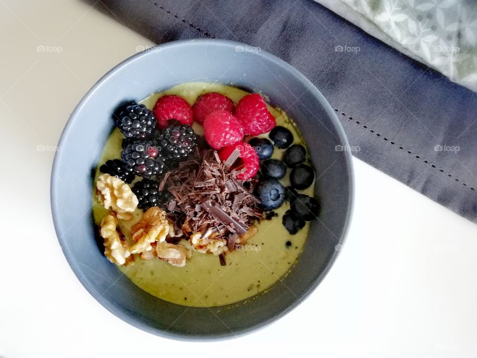 Matcha oats bowl with berries, chocolate and nuts